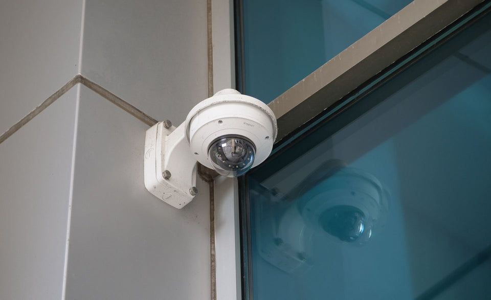 Dome security camera installed beside a modern glass facade